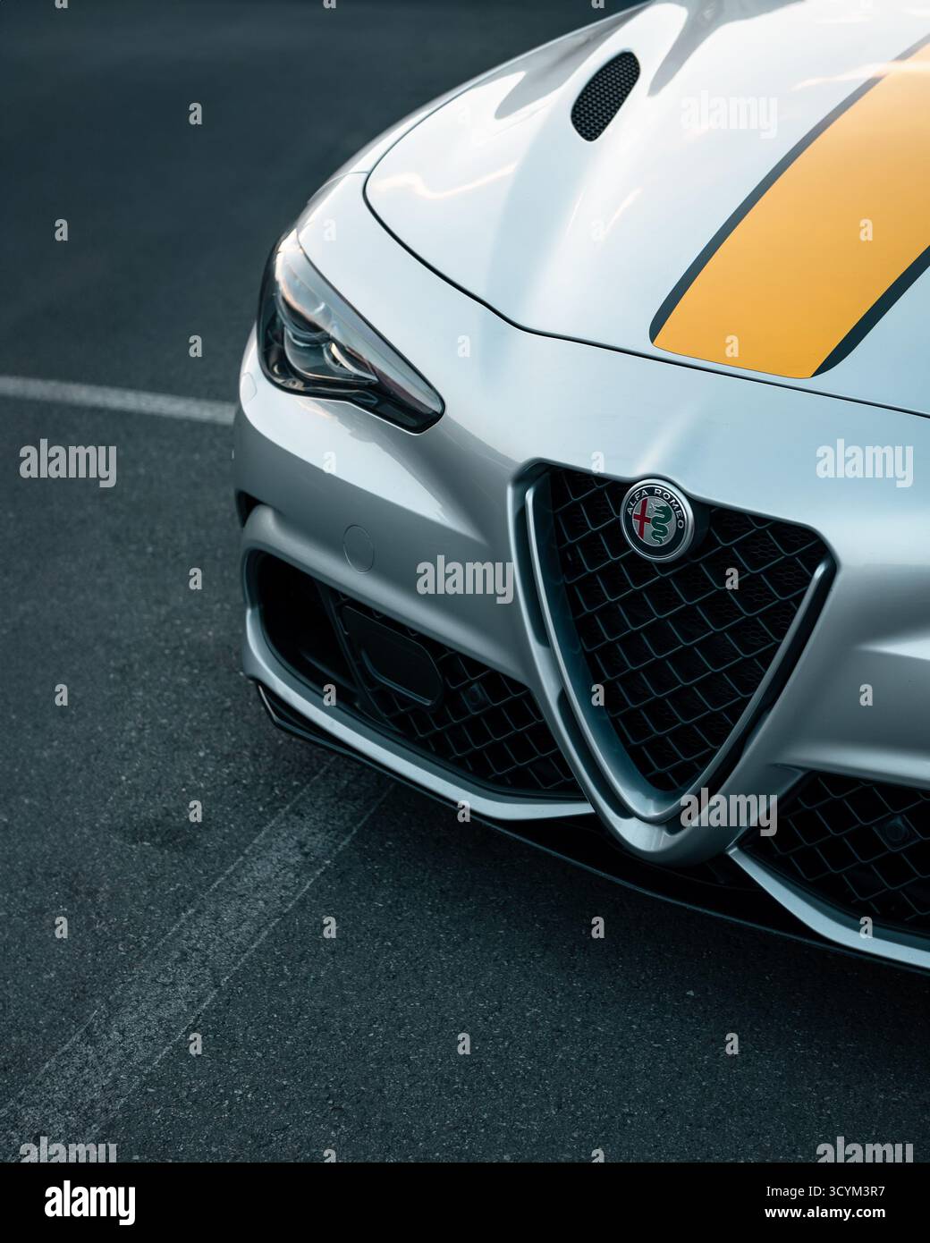 Partie avant en argent Alfa Romeo Giulia QV avec une bande jaune sur le capot. Gros plan de la berline sport italienne moderne. Banque D'Images