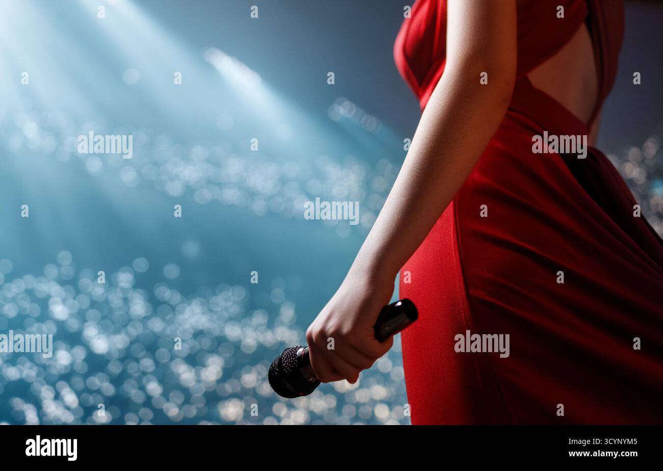 Un chanteur se produisant passionnément sur scène avec un microphone devant des lanternes de style bokeh, baigné de lumière vive et entouré par une atmosphère animée Banque D'Images