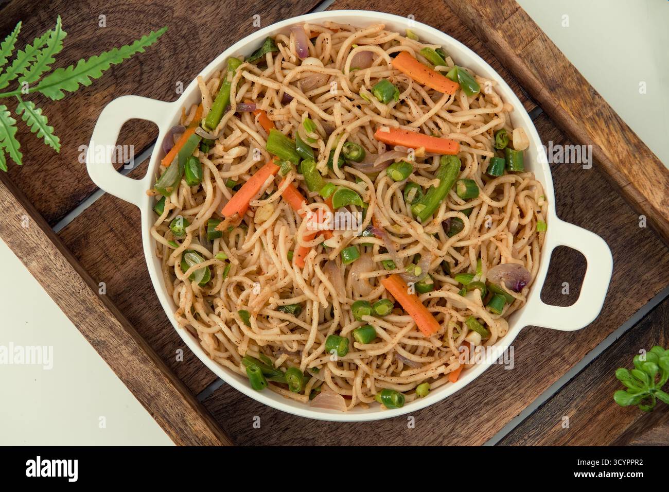 Savoureuses nouilles hakka aux légumes dans une assiette blanche et un fond isolé. Plat de cuisine végétarienne indo-chinoise. Nouilles végétales indiennes avec légumes. Banque D'Images