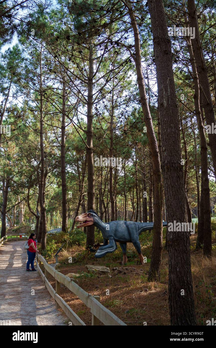 Une femme observe une sculpture grandeur nature de l'Utahraptor au parc à thème Dino Parque à Lourinhã, Portugal, Europe Banque D'Images