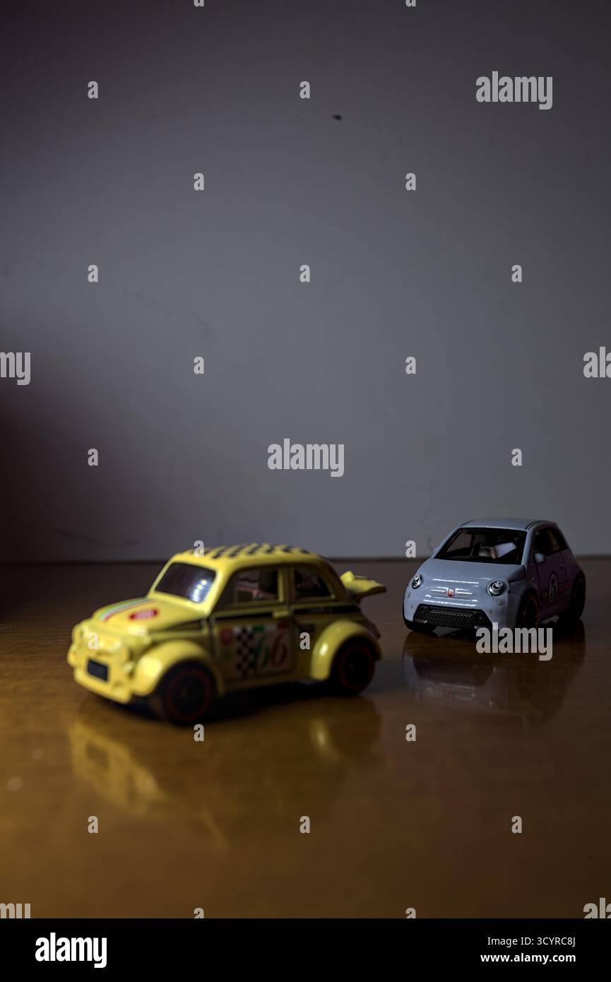 Mantova, Italie - 3RD SEPTEMBRE 2025 - Hot Wheels répliques d'une Fiat 500e et d'une Fiat 500d entre des bols en plastique prétendant avoir une course entre deux R. Banque D'Images