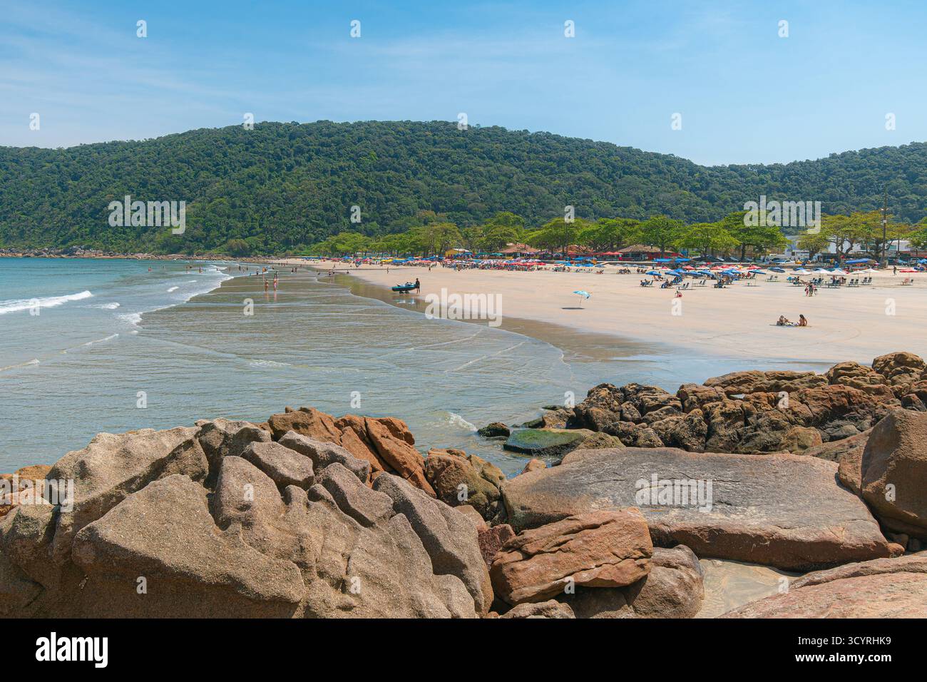 Plage de Guaiuba, Guaruja SP, Brésil. Journée ensoleillée sur la petite baie avec mer tranquille. Image des loisirs et du tourisme sur la côte de Sao Paulo. Collines couvertes Banque D'Images