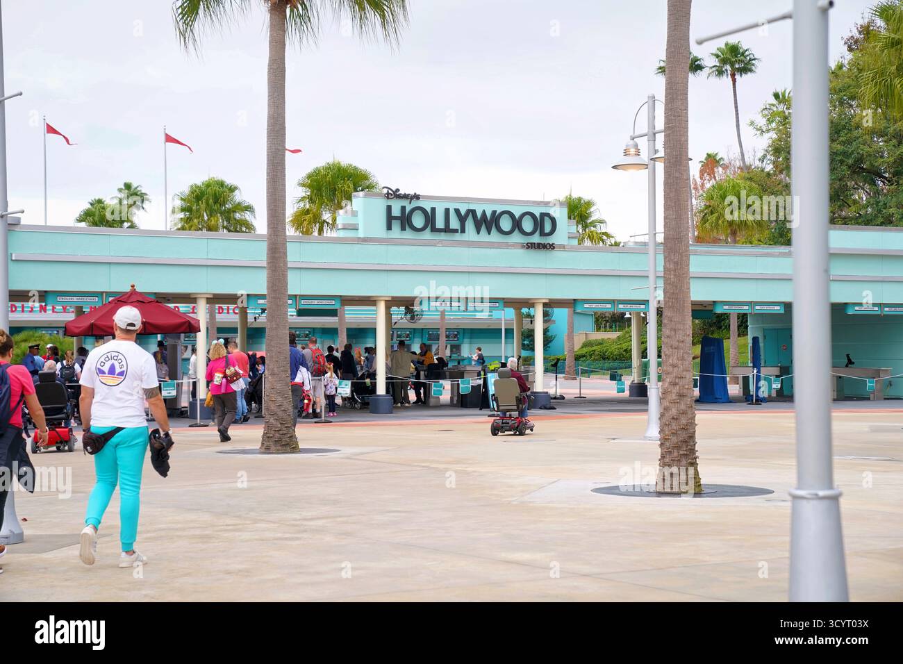 Les visiteurs approchent de l’entrée des studios Disney’s Hollywood, qui présentent une architecture art déco sarcelle et des palmiers sous un ciel nuageux Banque D'Images