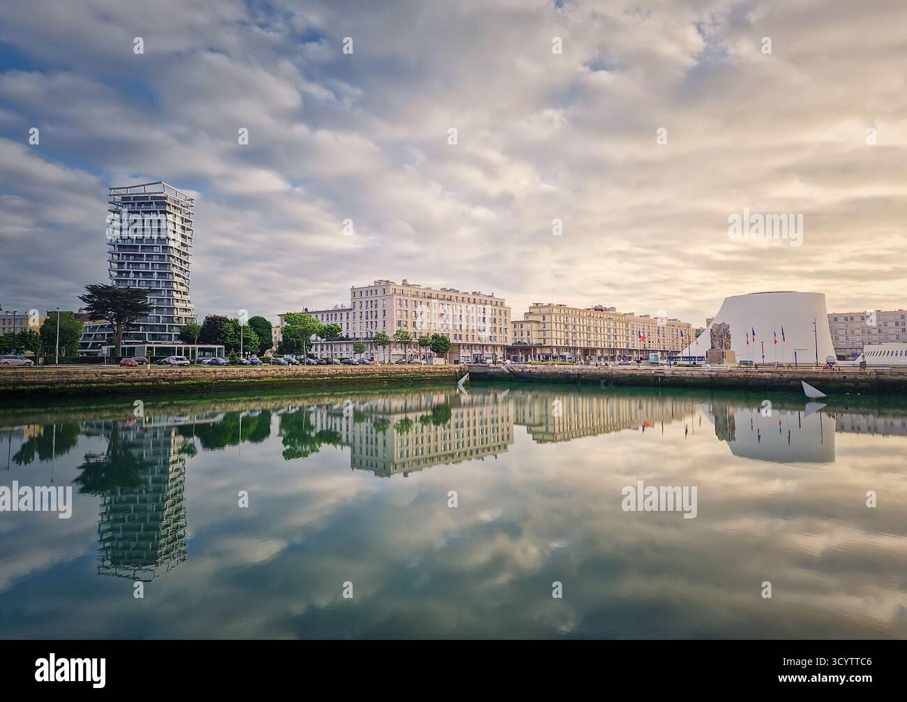 Belle scène de front de mer au Havre, France au coucher du soleil. Les bâtiments se reflètent parfaitement dans l'eau plate Banque D'Images