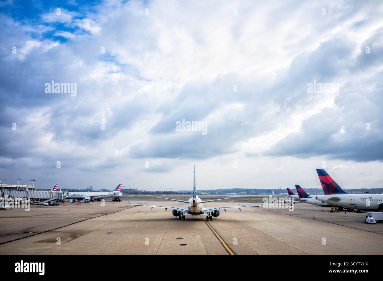 Les avions circulant sur Tarmac à l'aéroport national Reagan Washington DC // WASHINGTON DC — les avions roulent en taxi et sont garés sur le tarmac à l'aéroport national Ronald Reagan Washington. Un avion de ligne commercial se déplace sur l'aire de trafic, tandis que les avions American Airlines et Delta Airlines sont visibles à leurs portes. Ronald Reagan Washington National Airport (DCA) est un aéroport important desservant la région métropolitaine de Washington. Situé à Arlington, en Virginie, juste au sud du centre-ville de Washington, D.C. C'est l'aéroport commercial le plus proche de la capitale américaine. L'aéroport gère principalement les vols intérieurs et offre co Banque D'Images