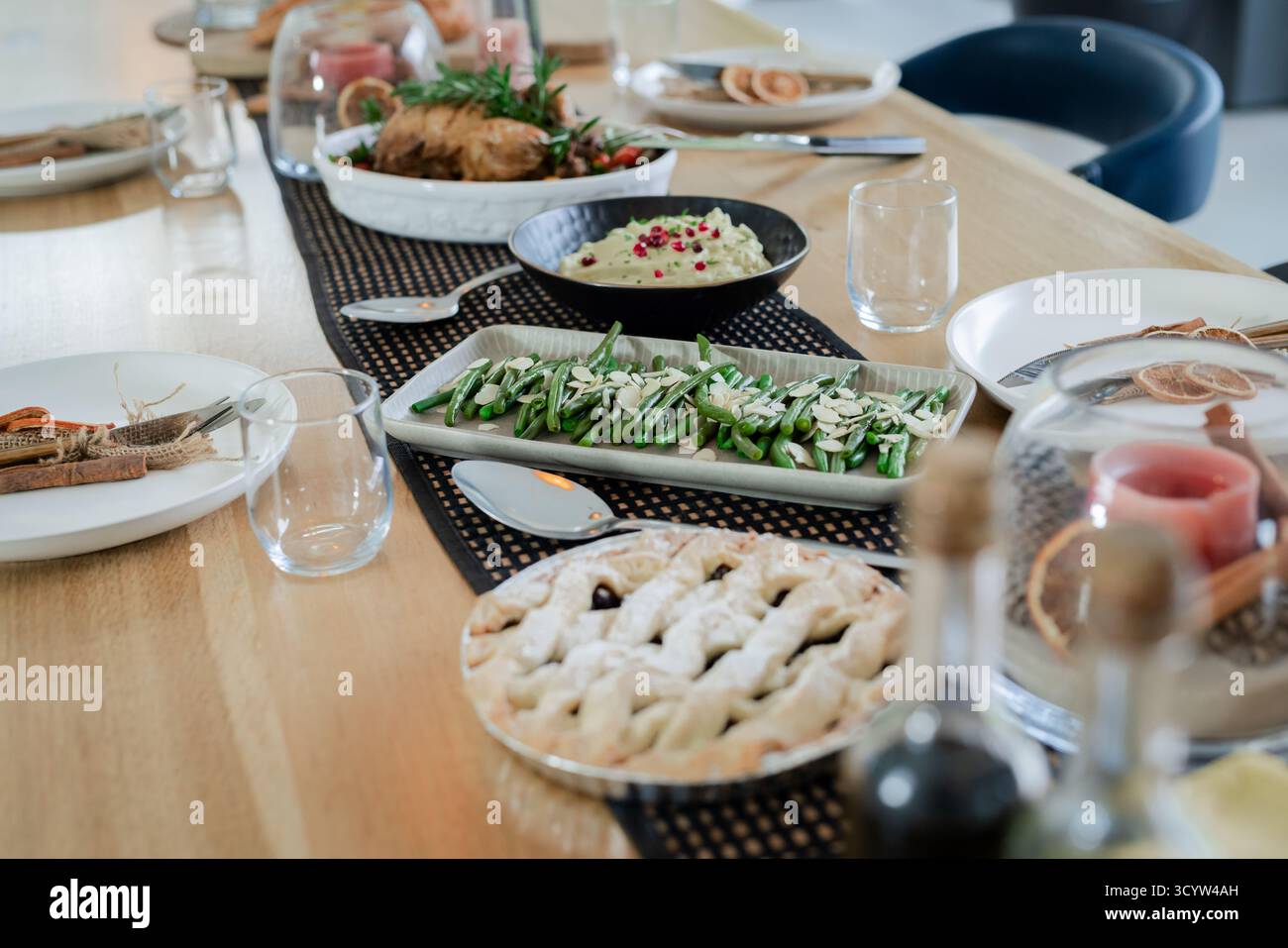 La table à manger présente une tarte en treillis, des haricots verts, de la viande rôtie et un dôme en verre dans la salle à manger Banque D'Images