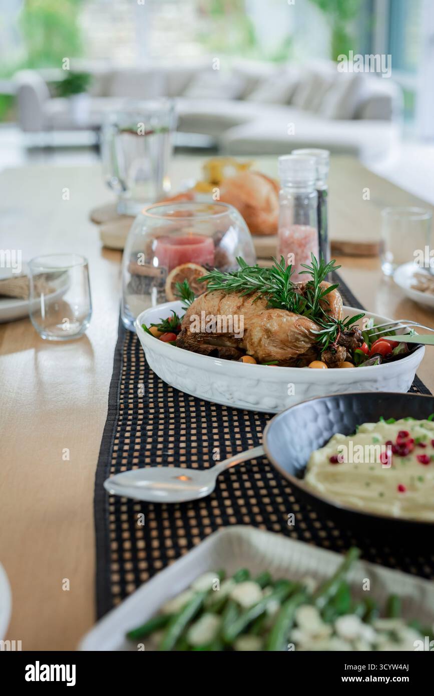 Table à manger en bois avec poulet rôti, purée de pommes de terre, haricots verts, pichet d'eau Banque D'Images