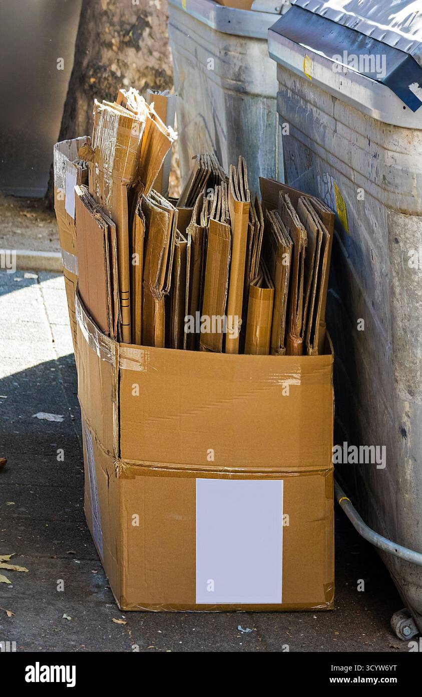 Pile de papier carton à l'intérieur de la boîte en carton à côté de la poubelle à l'extérieur sur la rue prêt pour le recyclage Banque D'Images
