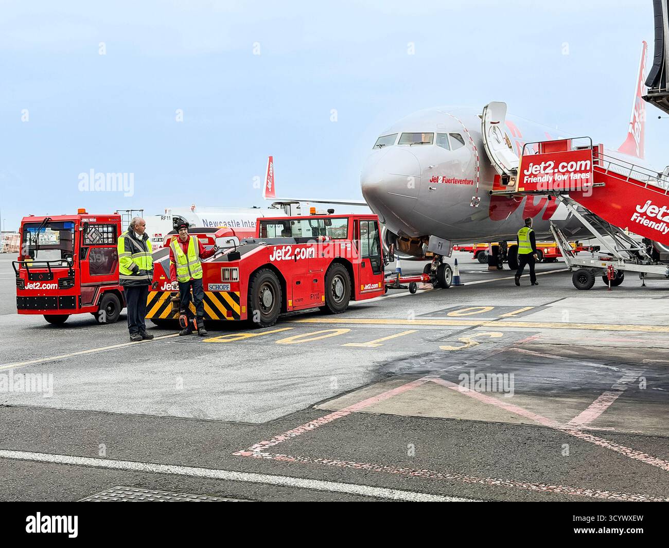 Équipage au sol de l'aéroport et véhicules préparant un avion Jet2 pour le départ à un terminal très fréquenté avec un ciel dégagé au-dessus - Image de stock capturée avec un smartphone