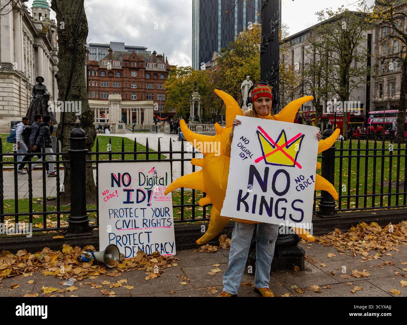 Un manifestant vêtu d'un costume de soleil arbore des signes anti-monarchie et anti-numérique d'identité lors d'une manifestation pour les droits civiques dans un centre-ville de Belfast le 18 octobre 25 Banque D'Images