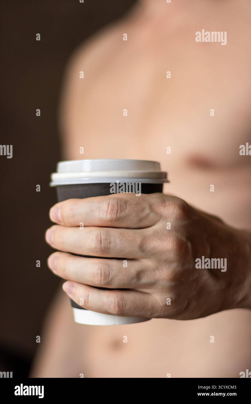 Mains tenant la tasse de café dans un moment calme. Gros plan de mains masculines berçant une tasse de café chaude, symbolisant la pause de travail à distance, rituel d'hygiène matinale Banque D'Images