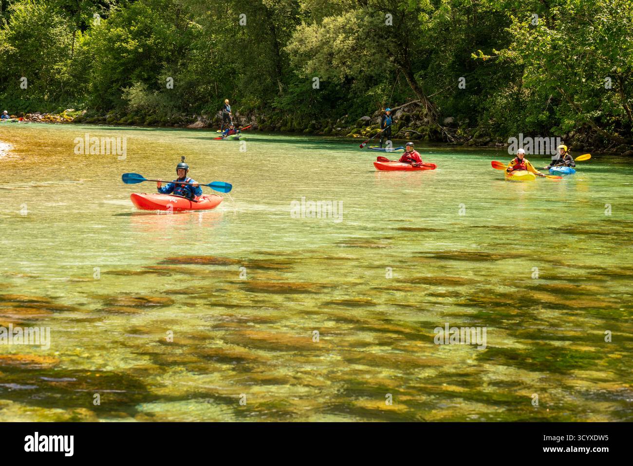 Kayakistes pagayant sur les eaux turquoises cristallines de la rivière Soča en Slovénie, profitant des sports nautiques de loisirs sous le soleil d'été Banque D'Images