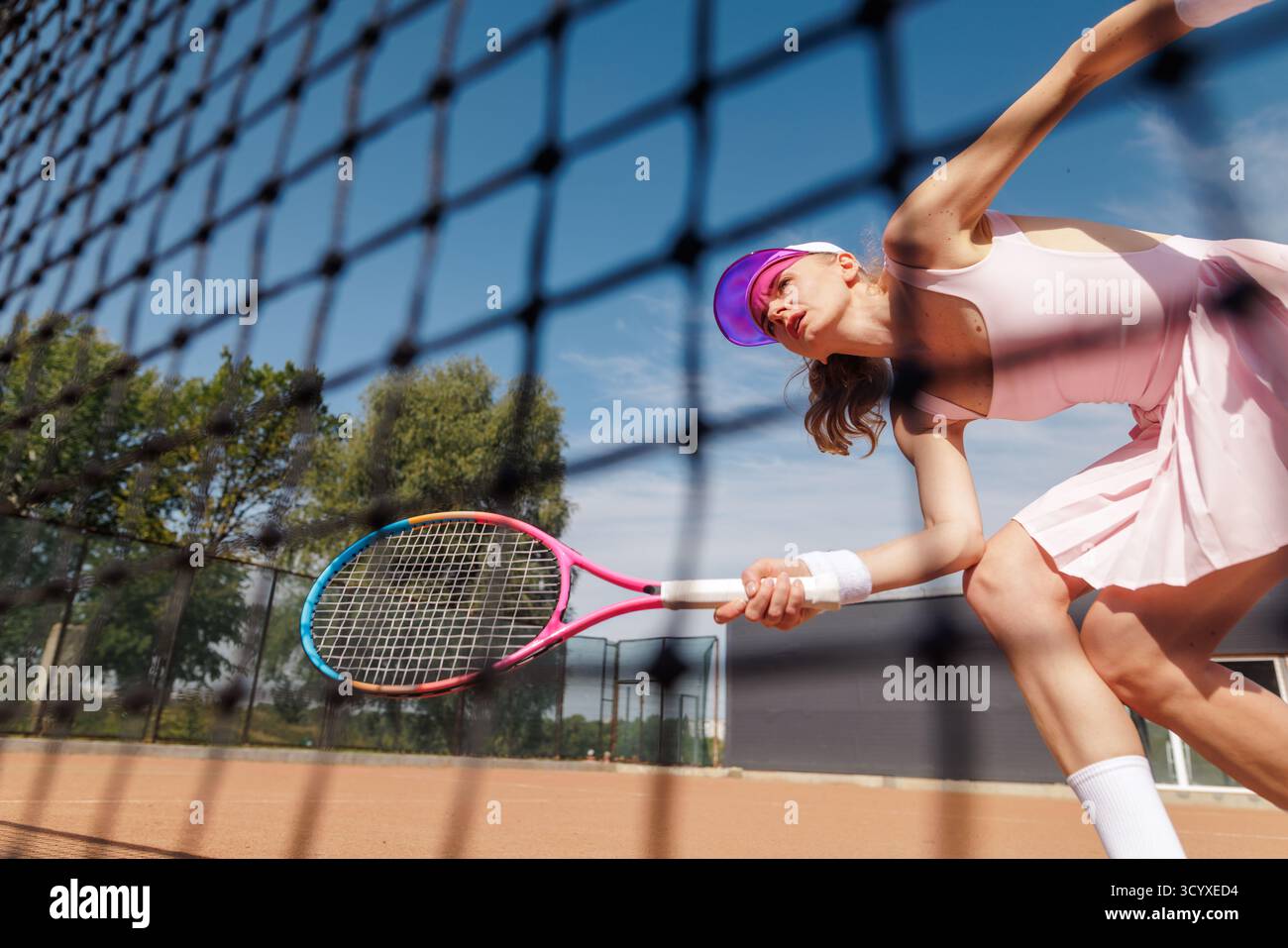 Vue dynamique à faible angle d'une athlète de tennis jouant un rallye sur le filet avec une action axée sur la raquette et de l'énergie sur un court de terre battue Banque D'Images
