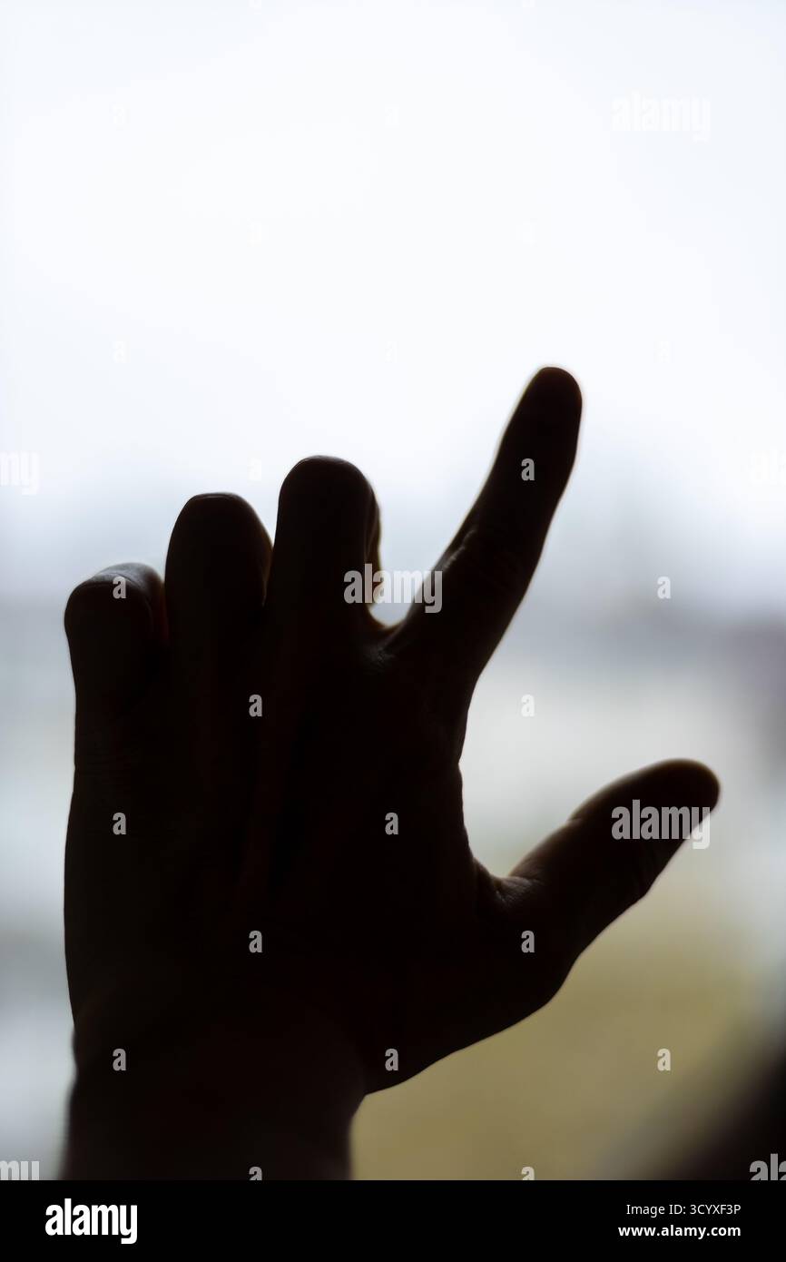 Silhouette main dans Shaka signe geste. Une silhouette décontractée rétro-éclairée d'une main formant un shaka ou accrocher un signe lâche contre le ciel, évoquant un posit décontracté Banque D'Images