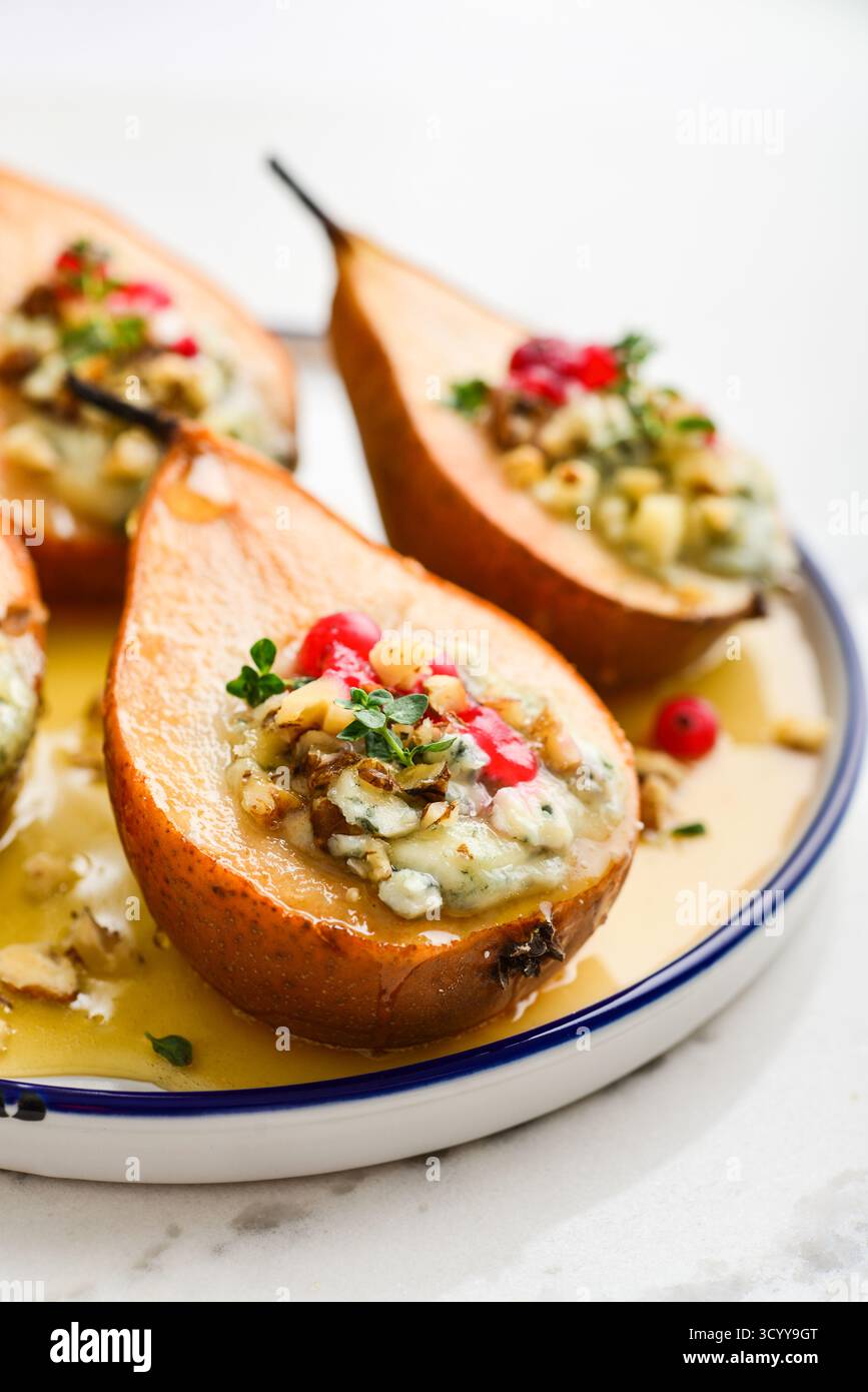 Délicieuses poires cuites au four avec des noix, du fromage bleu, du thym, de la canneberge et du miel sur fond clair en gros plan Banque D'Images
