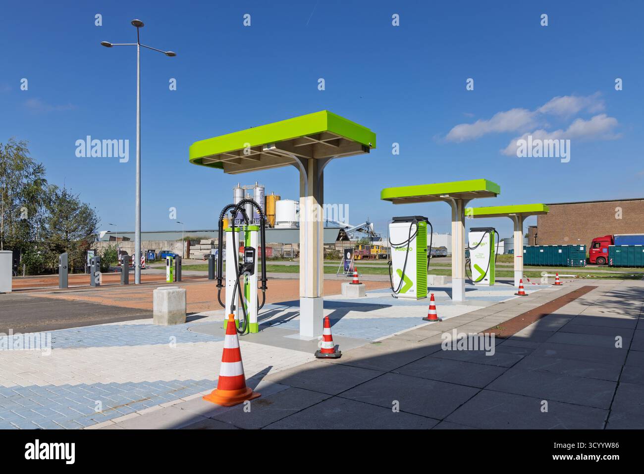 Station de recharge rapide Allego Electric Vehicle (EV) moderne avec verrière et piliers de recharge vert vif, située dans un environnement industriel. Banque D'Images