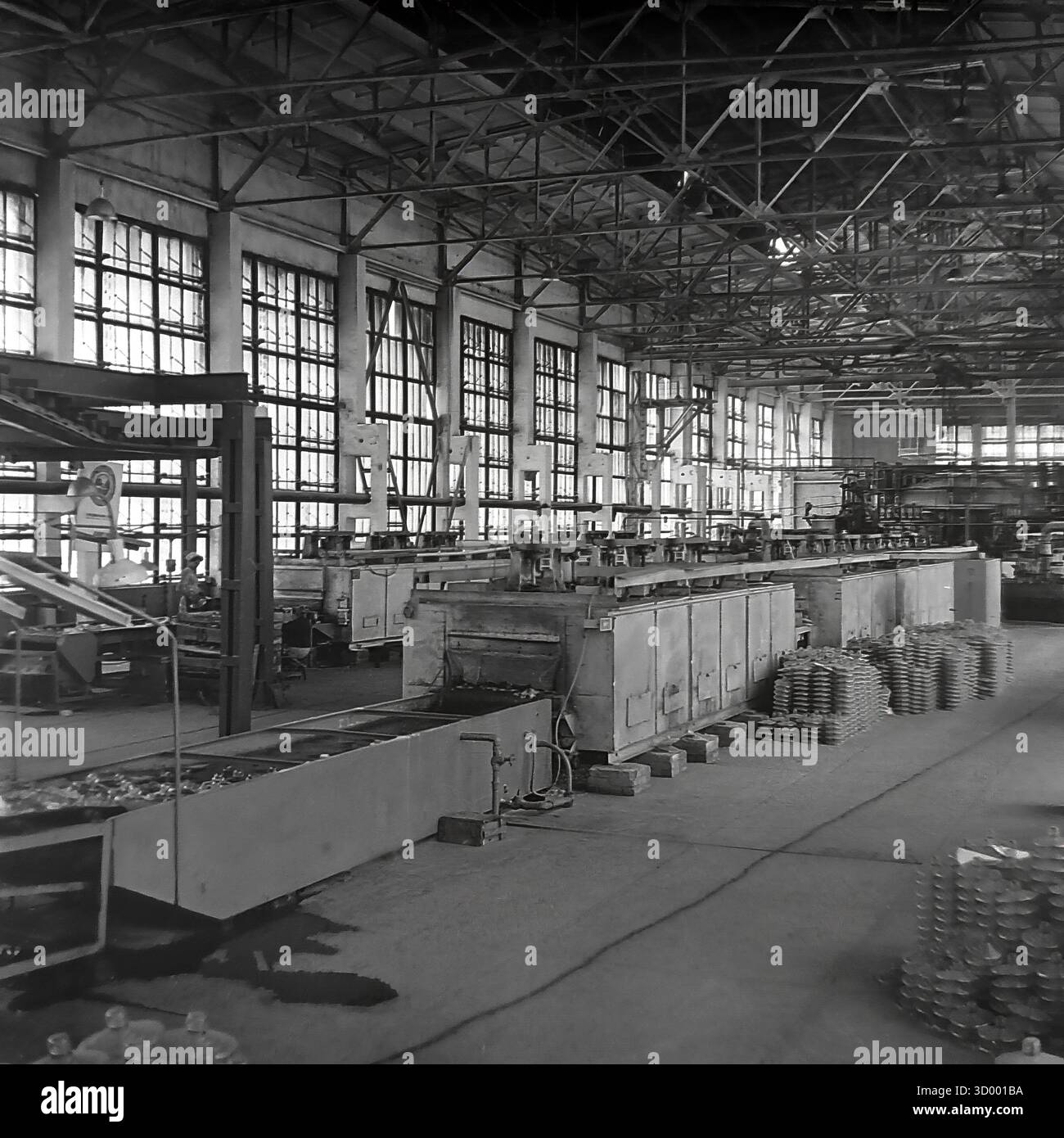 Cette photo d'archive de 1966 de Sloviansk, RSS d'Ukraine, montre l'intérieur d'un atelier massif à l'usine d'armature et d'isolateur (AIF). Le hall a un plafond haut en treillis et un mur de grandes fenêtres industrielles. Une longue ligne de production, probablement un lehr de recuit (four de refroidissement), est au centre. Les isolants finis en verre ou en céramique sont visibles sur le convoyeur et empilés sur le sol. Cette image capture l'échelle de la production de masse soviétique et de la technologie, un document clé du Donbass pacifique Banque D'Images