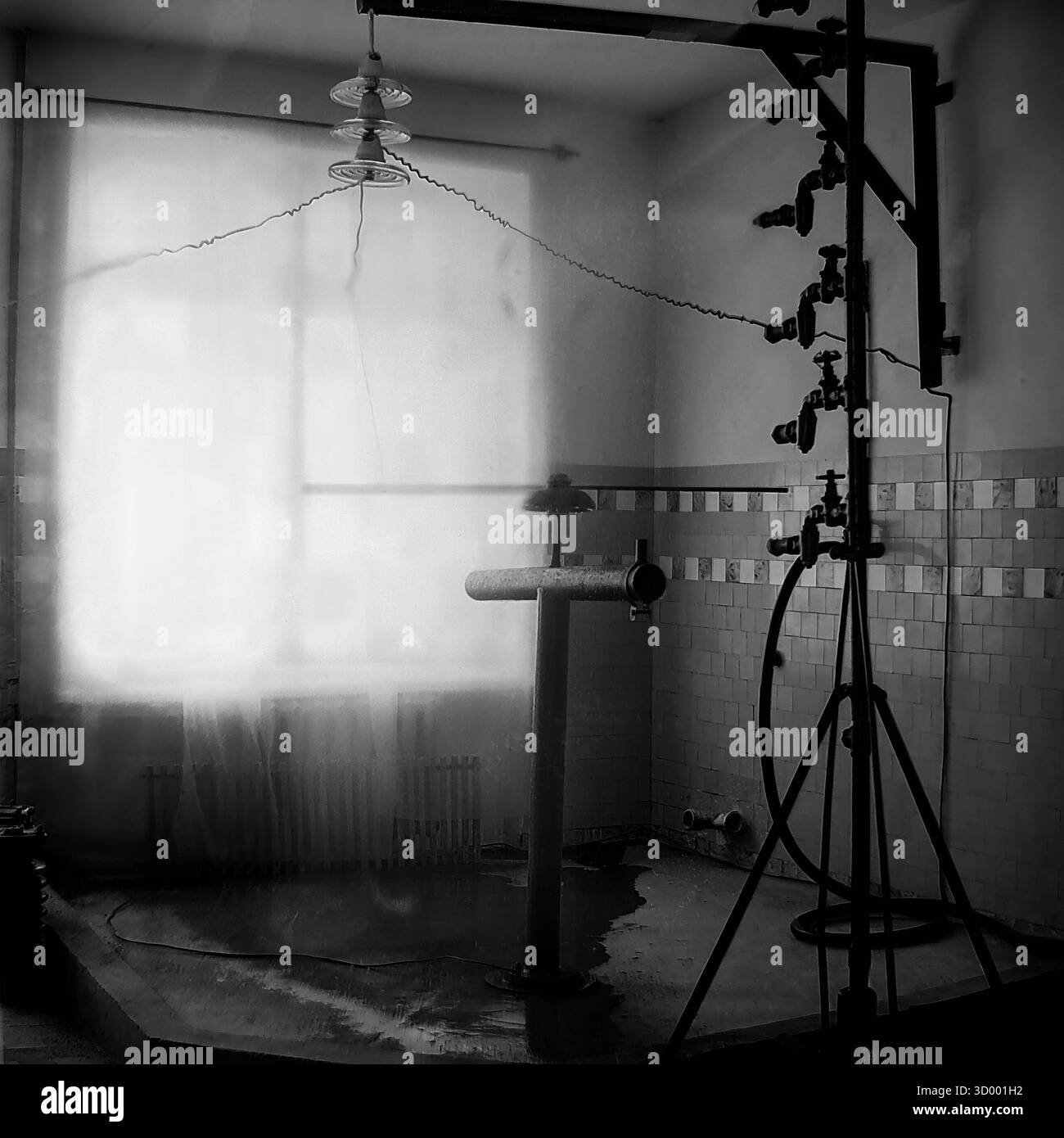 Cette photo d'archive de 1966 montre le laboratoire d'essai haute tension à l'usine d'armature et d'isolateur (AIF) à Sloviansk, RSS d'Ukraine. Cette salle spécialisée « test de pluie » était destinée au contrôle de la qualité. Un isolant en verre est suspendu au plafond, câblé pour les tests. À droite se trouve un engin complexe avec des buses conçues pour pulvériser de l'eau, simulant la pluie sur le produit. Le sol carrelé est mouillé par la procédure. Cette image montre le côté scientifique et technique avancé de l'industrie lourde soviétique, un document clé du Donbass pacifique Banque D'Images