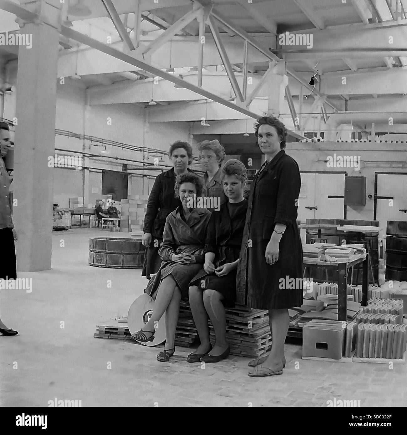 Cette photo d'archive de 1966 de Sloviansk, RSS d'Ukraine, montre un portrait de groupe de travailleuses à l'usine d'armature et d'isolateur (AIF). Cinq femmes, probablement une brigade, posent ensemble dans un atelier lumineux et spacieux. Ils sont habillés dans une tenue de travail simple. L'environnement propre et moderne, avec son haut plafond en treillis et des piles ordonnées de produits finis (éventuellement des carreaux de céramique), contraste avec les scènes typiques de l'industrie lourde. Cette image met en évidence le rôle des femmes et l'esprit collectif dans le travail soviétique, un document du Donbass pacifique Banque D'Images