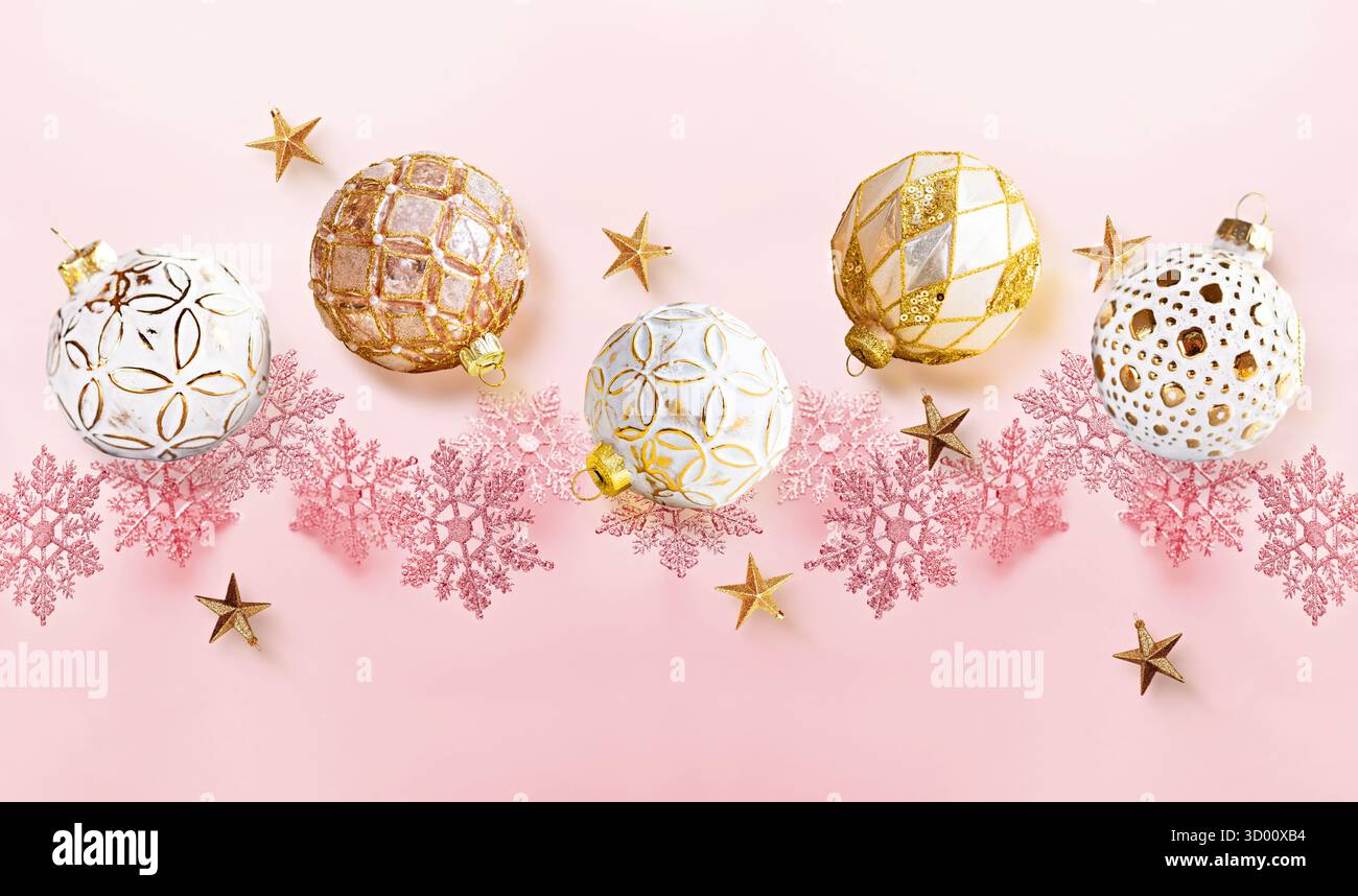 Ornements d'or et flocons de neige roses sur fond rose pastel Banque D'Images