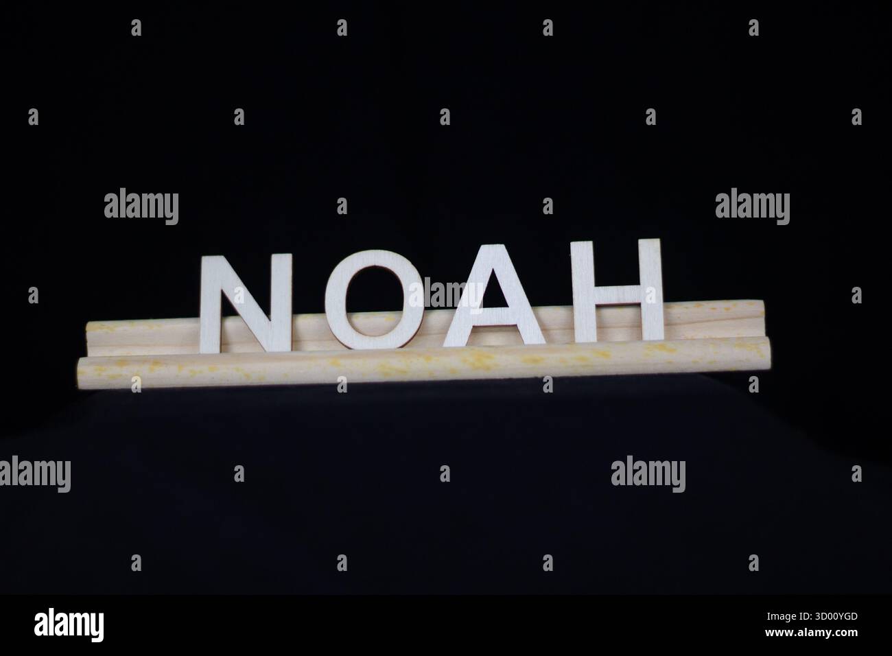 Noah nom de garçon traditionnel en lettres en bois ordinaire sur un support de tuiles isolé sur un fond noir Banque D'Images