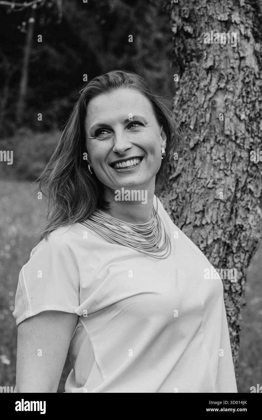 Heureuse femme d'âge moyen appréciant la nature et s'embrassant dans le champ de printemps. Concept d'amour de soi, santé féminine, équilibre émotionnel, pleine conscience, an Banque D'Images