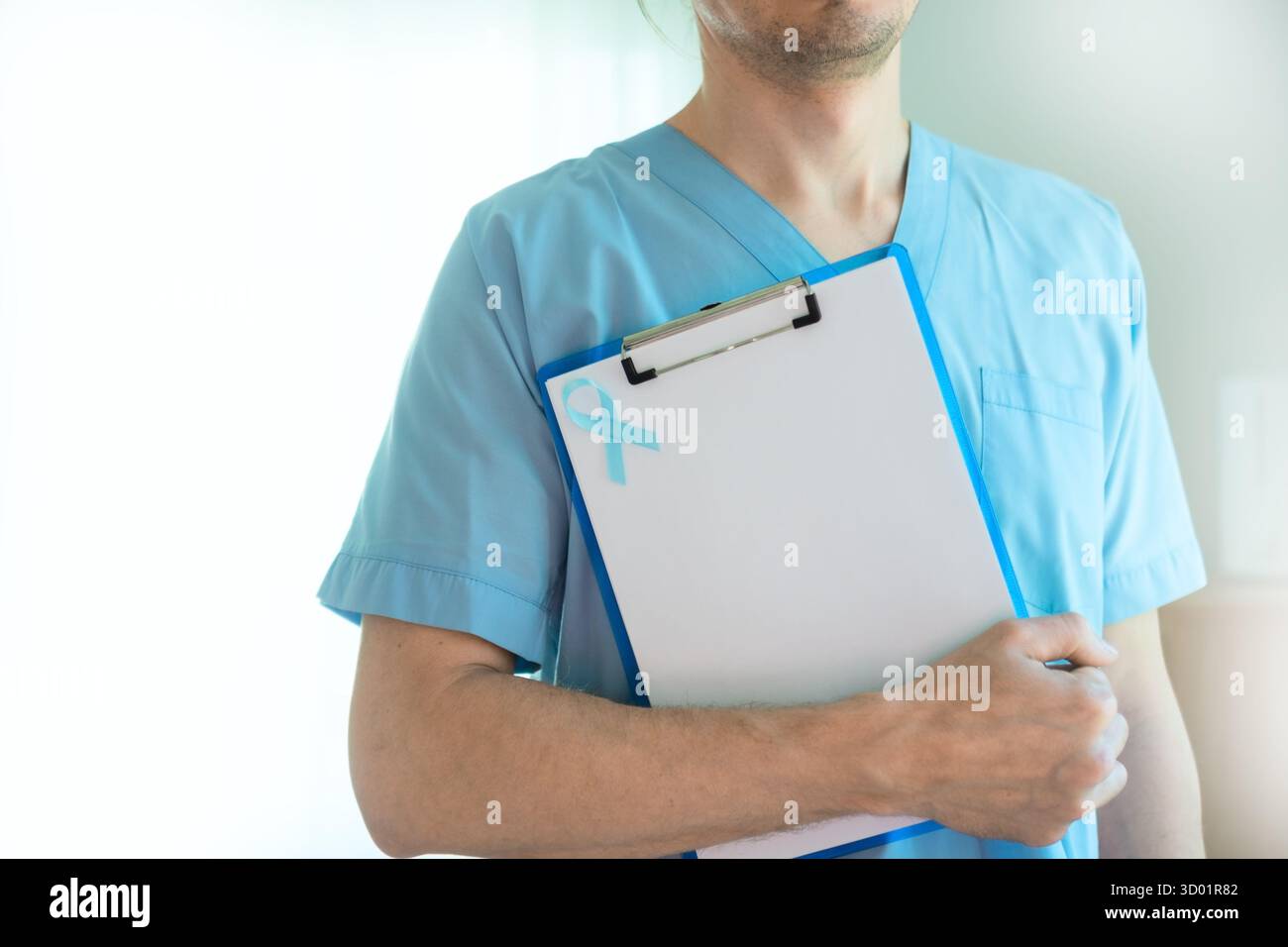 Médecin ou membre du personnel médical en uniforme tenant une planche à pince avec ruban bleu et papier blanc. Symbole de sensibilisation au cancer de la prostate, de prévention de la santé et de diagnostic précoce en novembre. Banque D'Images