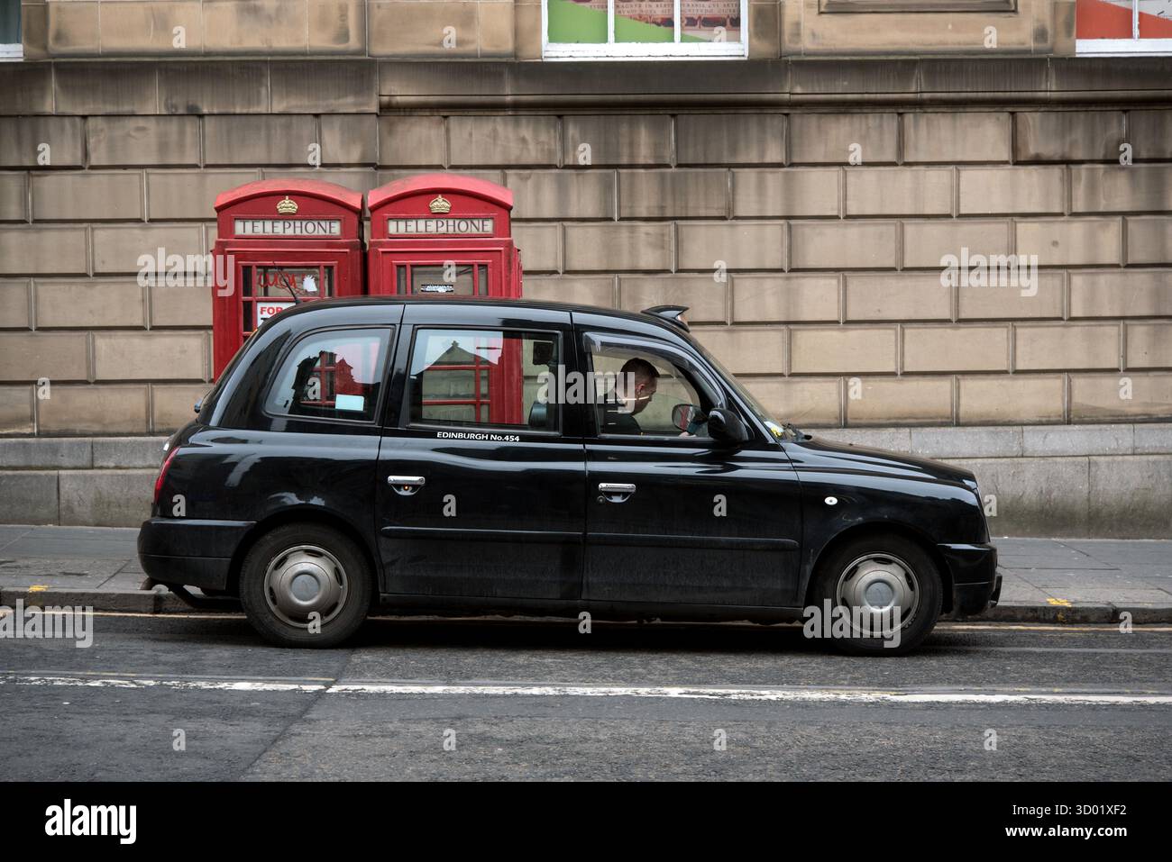 Taxi noir garé à côté des cabines téléphoniques rouges sur le pont George IV dans la vieille ville d'Édimbourg. Banque D'Images