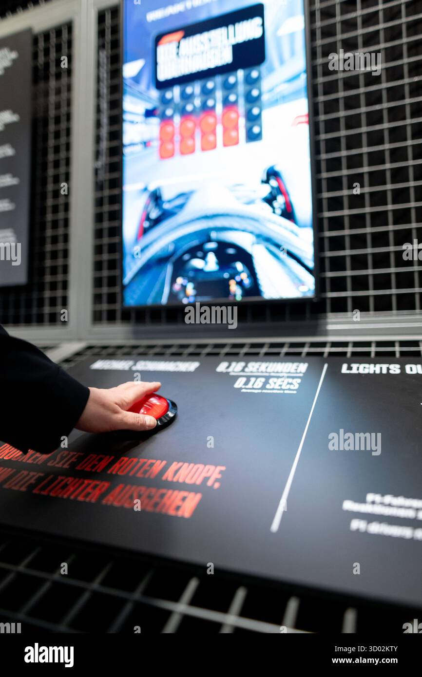 Oberhausen, Allemagne. 21 octobre 2025. Les visiteurs jouent le test de réaction dans l'exposition. Plus de 3 000 mètres carrés d'espace à l'OBEX Oberhausen Expo offrent un aperçu du monde de la course automobile. À partir du 22 octobre, le champion du monde Ferrari F1-2000 de Michael Schumacher sera exposé. Crédit : Fabian Strauch/dpa/Alamy Live News Banque D'Images