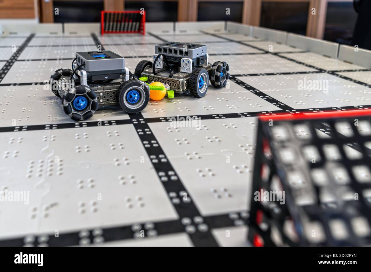Deux petits robots s'affrontent sur une grille de classe, mettant en valeur la technologie. Banque D'Images