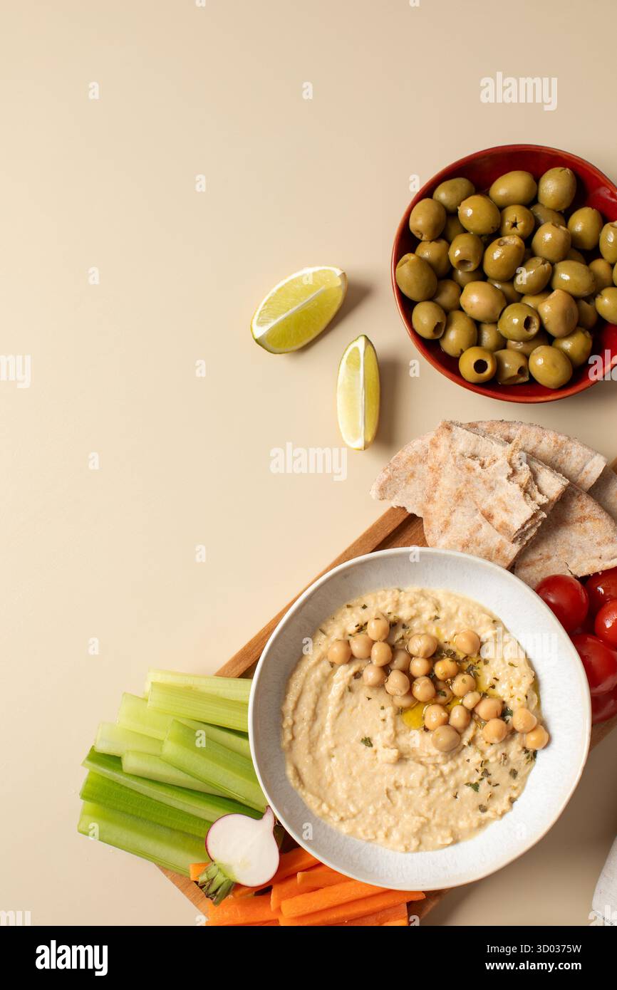 Houmous frais dans un bol sur une planche de bois avec pita, céleri et carottes. Plats de pois chiches, plat végétarien. Nourriture saine. Copier l'espace Banque D'Images