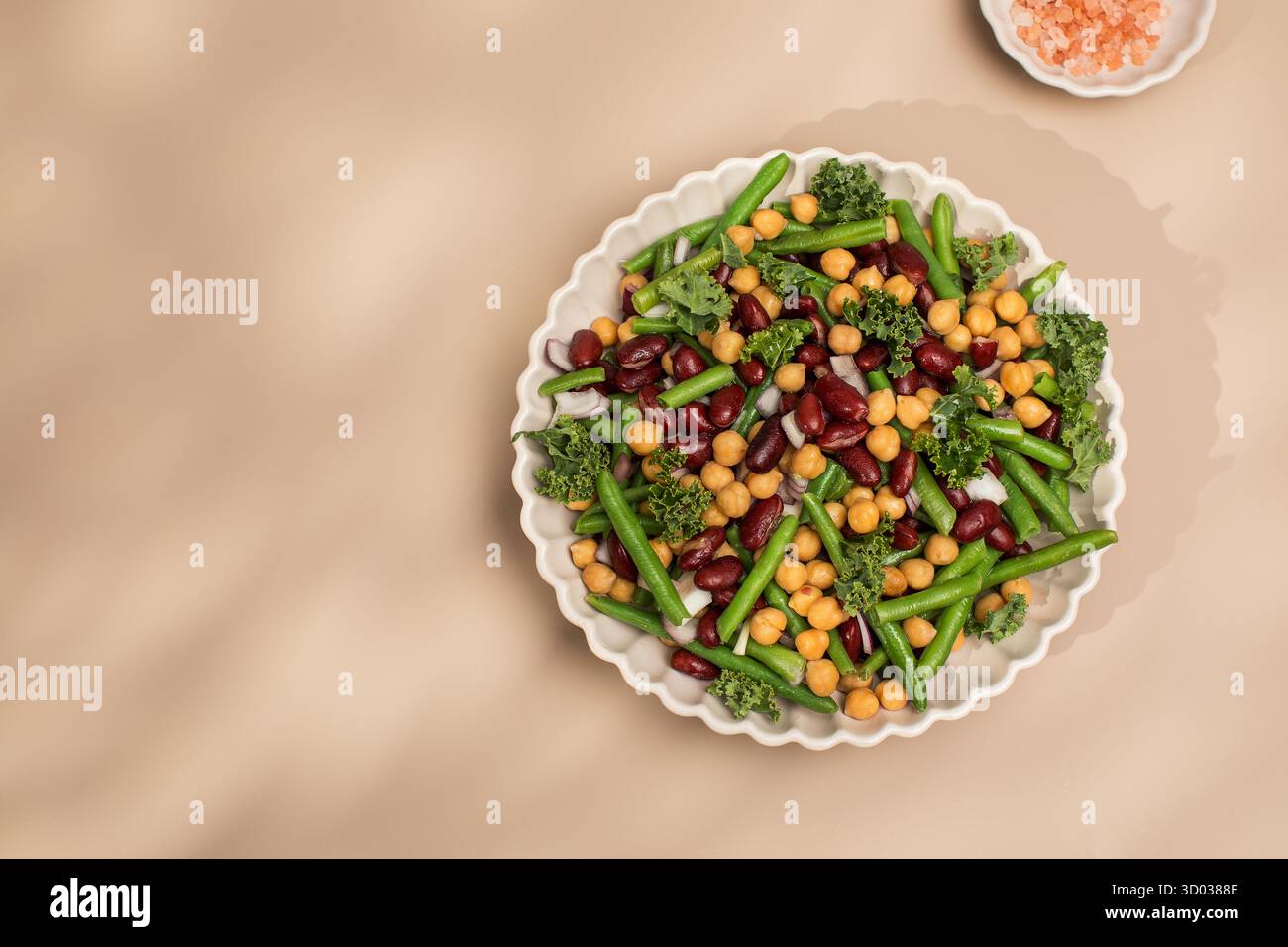 Salade fraîche de haricots mélangés et pois chiches avec sel rose de l'Himalaya sur fond beige. Concept de plats végétariens riches en protéines végétales. Nourriture saine. Copier l'espace Banque D'Images