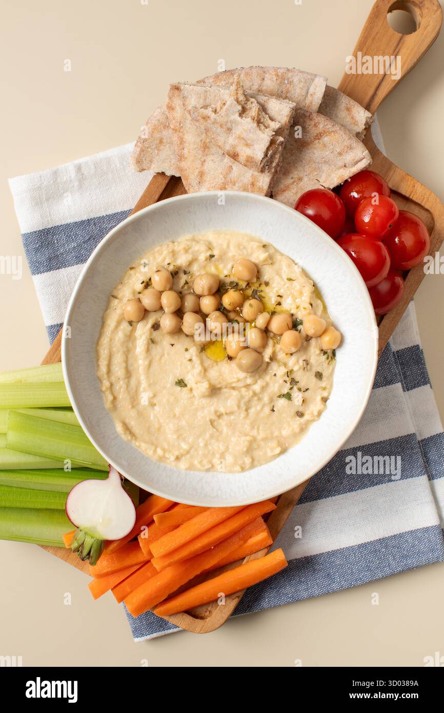 Houmous frais dans un bol sur une planche de bois avec pita, céleri et carottes. Plats de pois chiches, plat végétarien. Nourriture saine Banque D'Images