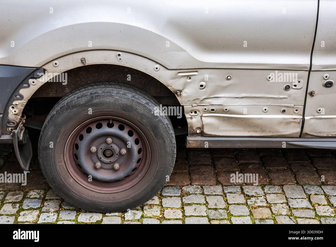 Kiel, Allemagne 15 mars 2025, gros plan d'une camionnette blanche endommagée garée dans une rue pavée, mettant en évidence l'aile et le pneu endommagés Banque D'Images