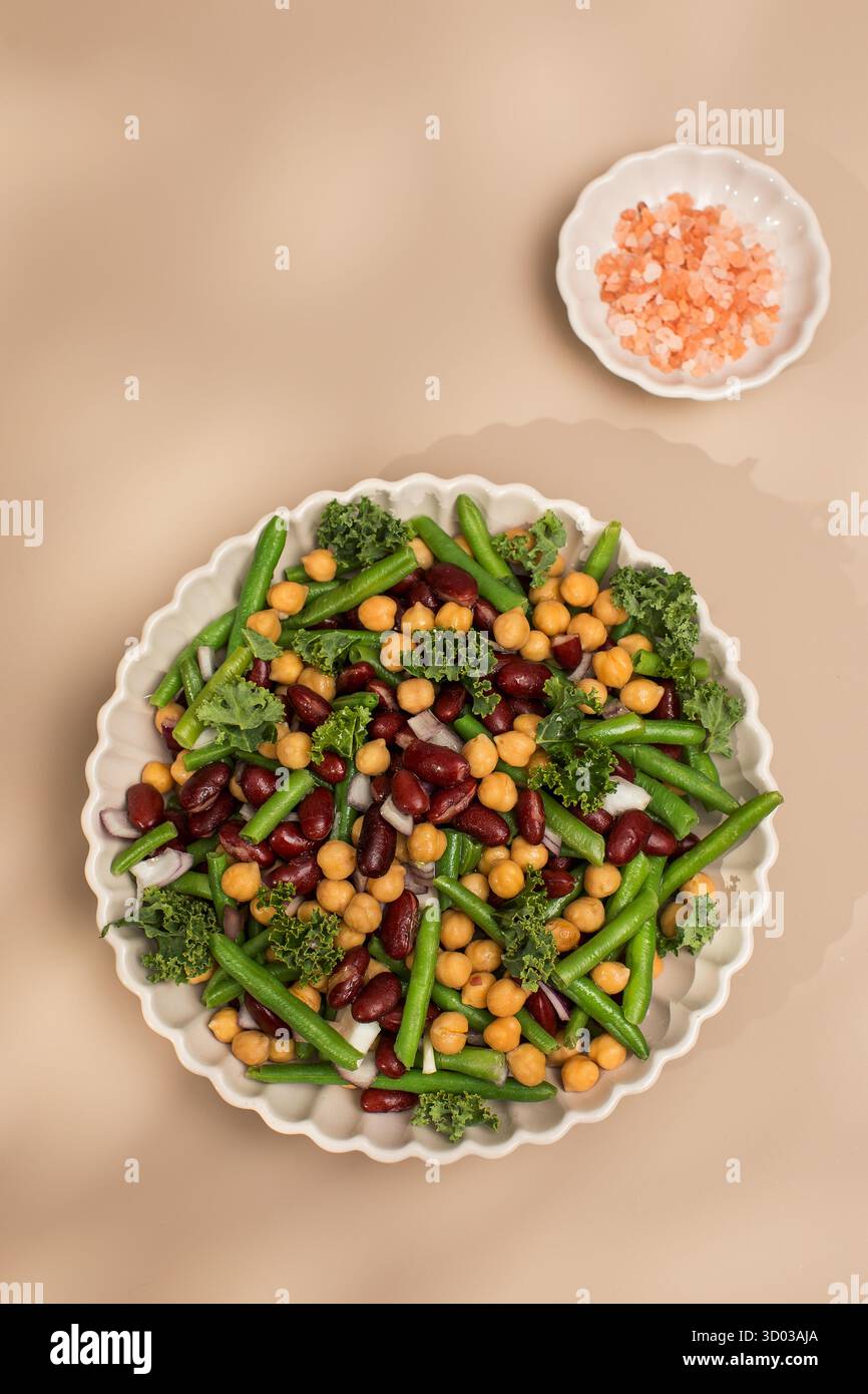Salade mixte fraîche de haricots et pois chiches sur fond beige. Le concept de plats végétariens riches en protéines végétales. Nourriture saine Banque D'Images