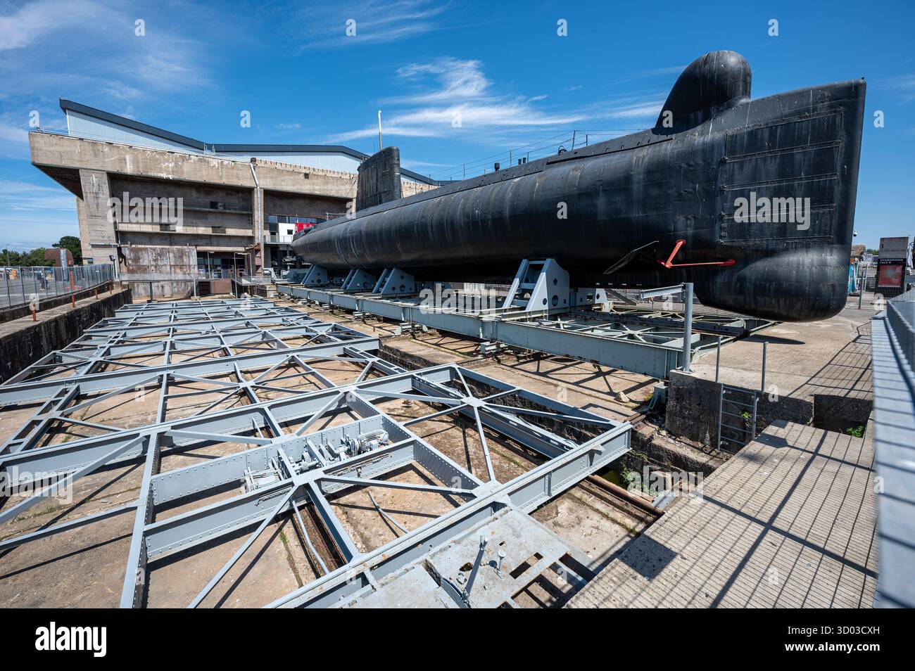 Plan large d'un sous-marin désarmé amarré à la base sous-marine historique de Lorient, avec la structure massive en béton et le ciel bleu clair Banque D'Images