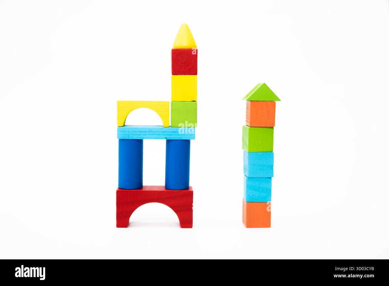 Blocs de jouet en bois colorés empilés et disposés dans des structures créatives sur un fond blanc. Concept éducatif et créatif. Banque D'Images