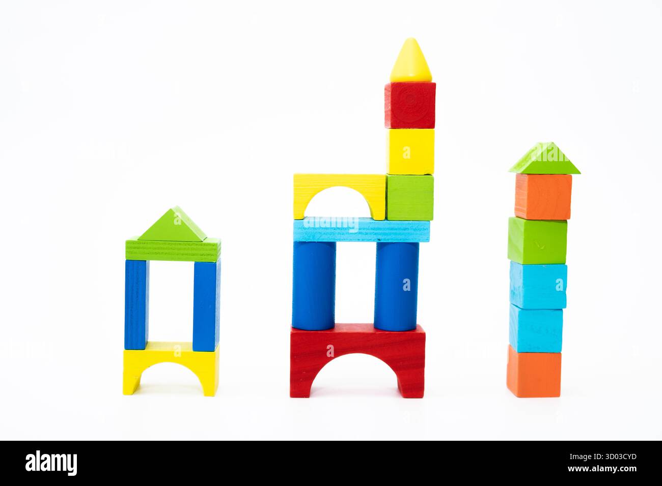 Blocs de bois aux couleurs vives empilés en trois formes uniques sur un fond blanc, représentant la créativité et l'apprentissage. Banque D'Images