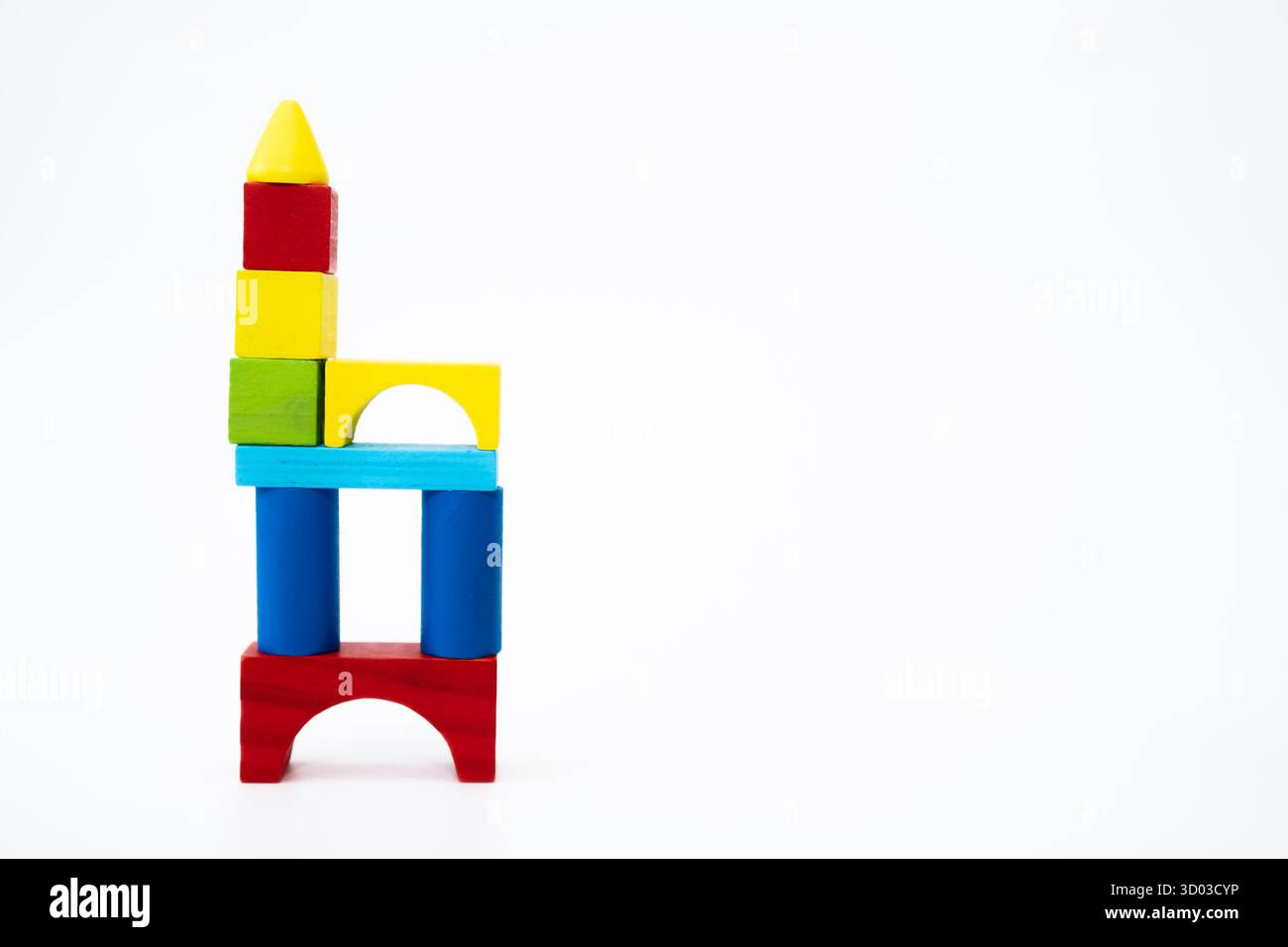 Blocs de bois colorés empilés dans une structure en forme de tour sur un fond blanc, représentant la créativité et le jeu éducatif. Banque D'Images