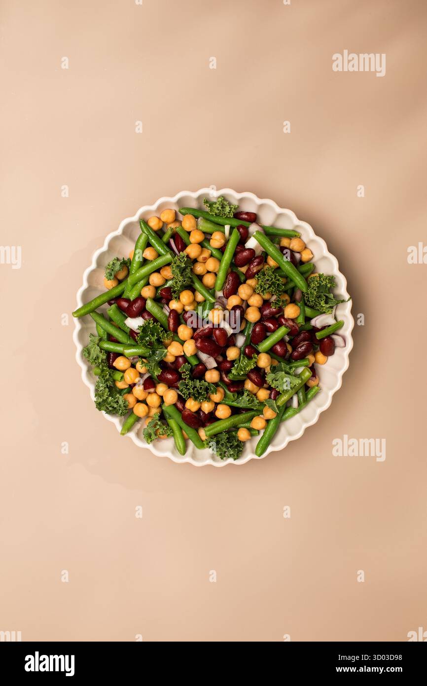 Salade mixte fraîche de haricots et pois chiches sur fond beige. Le concept de plats végétariens riches en protéines végétales. Nourriture saine Banque D'Images