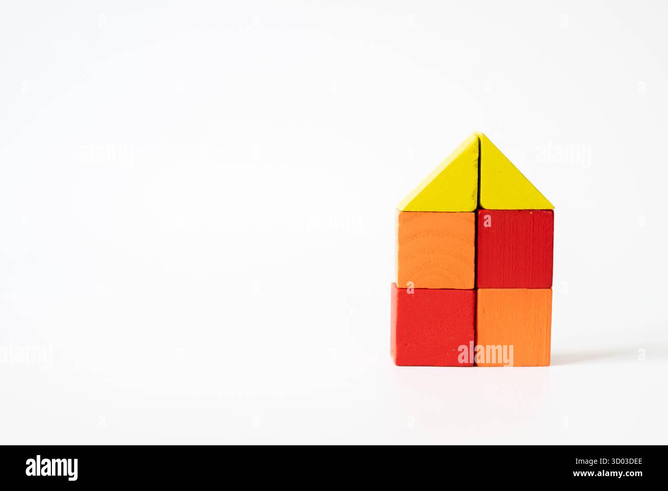 Une forme de maison créative faite de blocs de bois colorés sur un fond blanc, idéal pour les concepts de la maison, de l'enfance et de la créativité. Banque D'Images