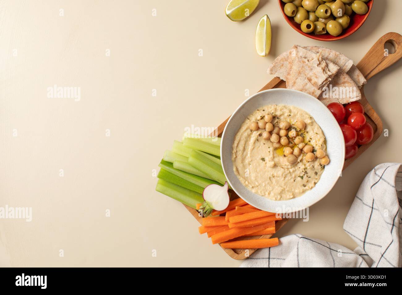 Houmous frais dans un bol sur une planche de bois avec pita, céleri et carottes. Plats de pois chiches, plat végétarien. Nourriture saine. Copier l'espace Banque D'Images