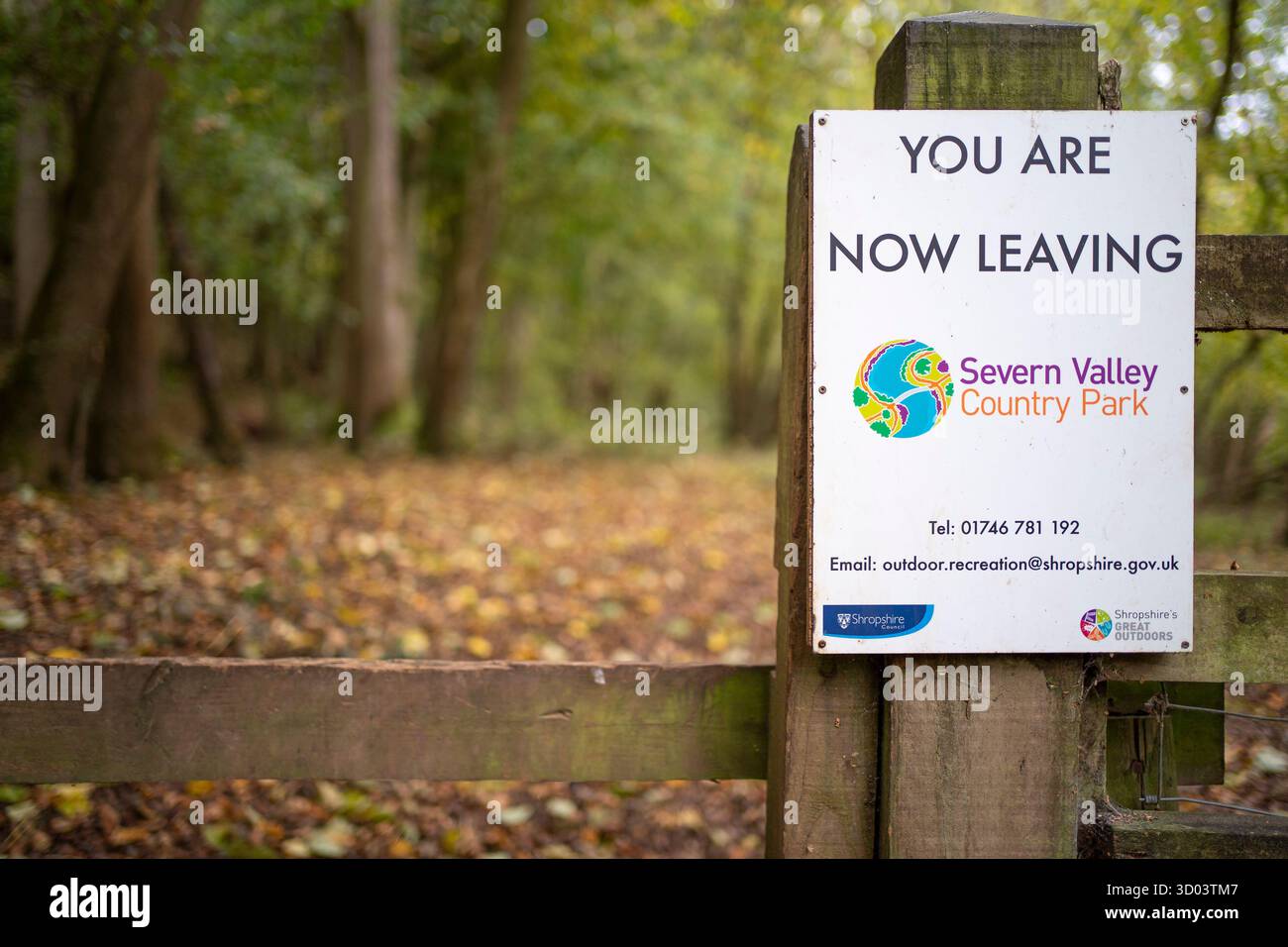 Gros plan d'un panneau sur une porte de campagne disant « vous quittez maintenant le parc rural de Severn Valley ». Les feuilles d'automne sont réparties sur le sol forestier. Banque D'Images