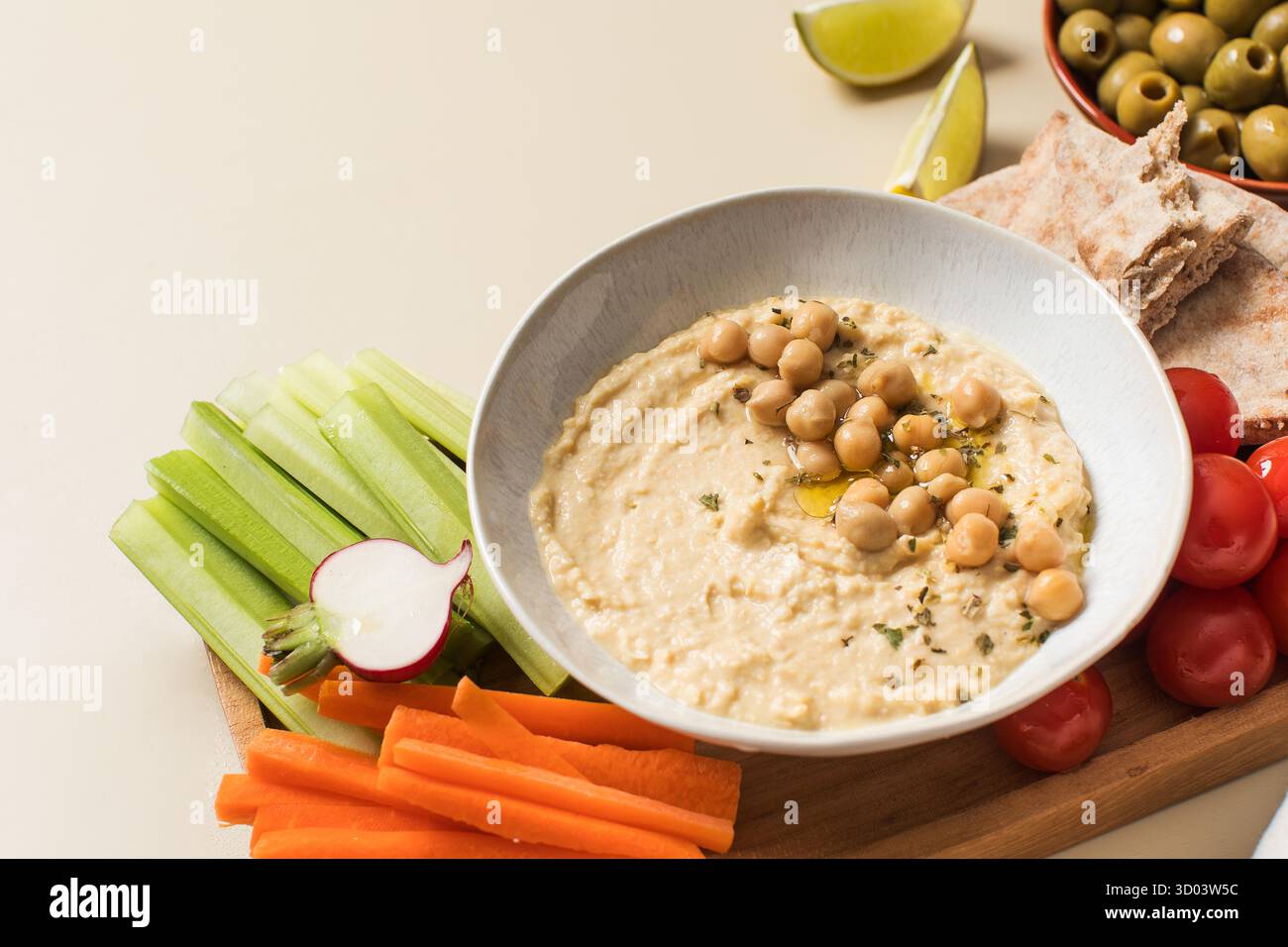 Houmous frais dans un bol sur une planche de bois avec pita, céleri et carottes. Plats de pois chiches, plat végétarien. Nourriture saine. Copier l'espace Banque D'Images