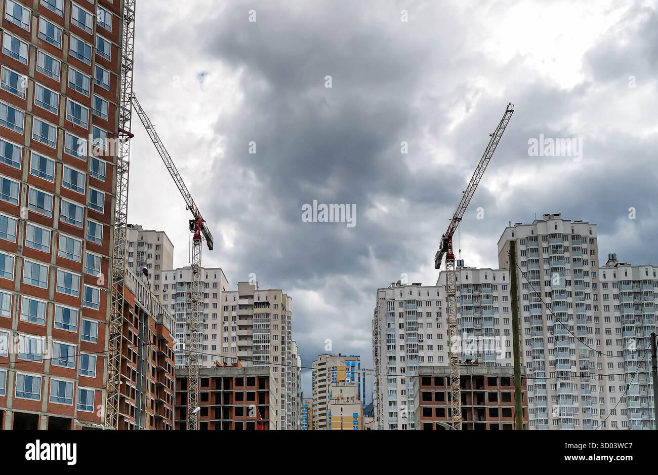 Chantier de construction urbaine avec grues imposantes et bâtiments résidentiels modernes, mettant en valeur le développement dynamique de l'architecture urbaine contre A. Banque D'Images