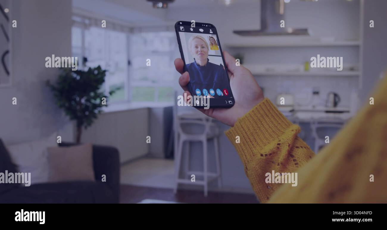 Tenant smartphone affichant la mère bavardant dans l'espace de vie, avec canapé gris, plante, tabourets de l'île Banque D'Images