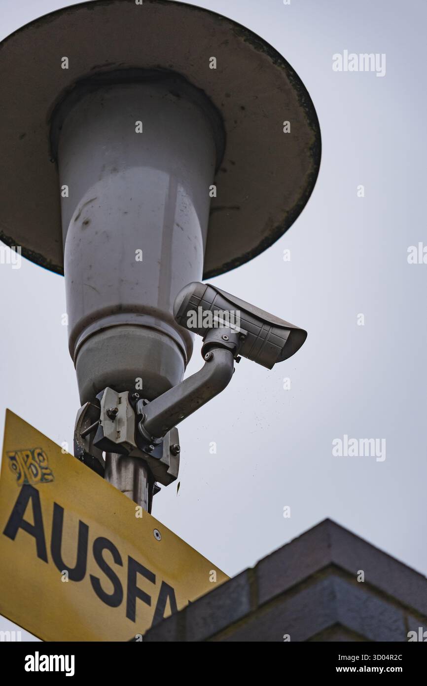 Gros plan d'une caméra de sécurité montée sur un poteau sous un ciel couvert Banque D'Images