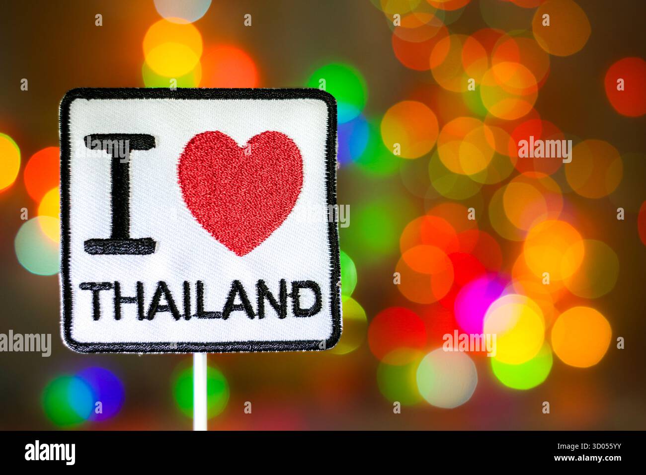 Signe « I Love Thailand » brodé contre des lumières bokeh colorées. Voyages asiatiques, promotion du tourisme et thèmes nationaux d'affection. Banque D'Images