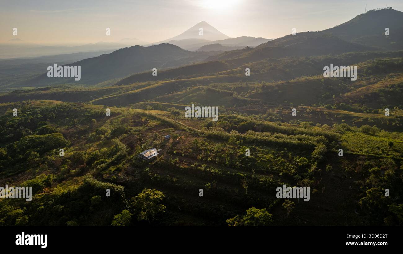 Superbe photo aérienne capture un vaste paysage de montagne brumeux à Flores au lever du soleil. La lumière dorée illumine les collines avec une petite cabane, menant Banque D'Images