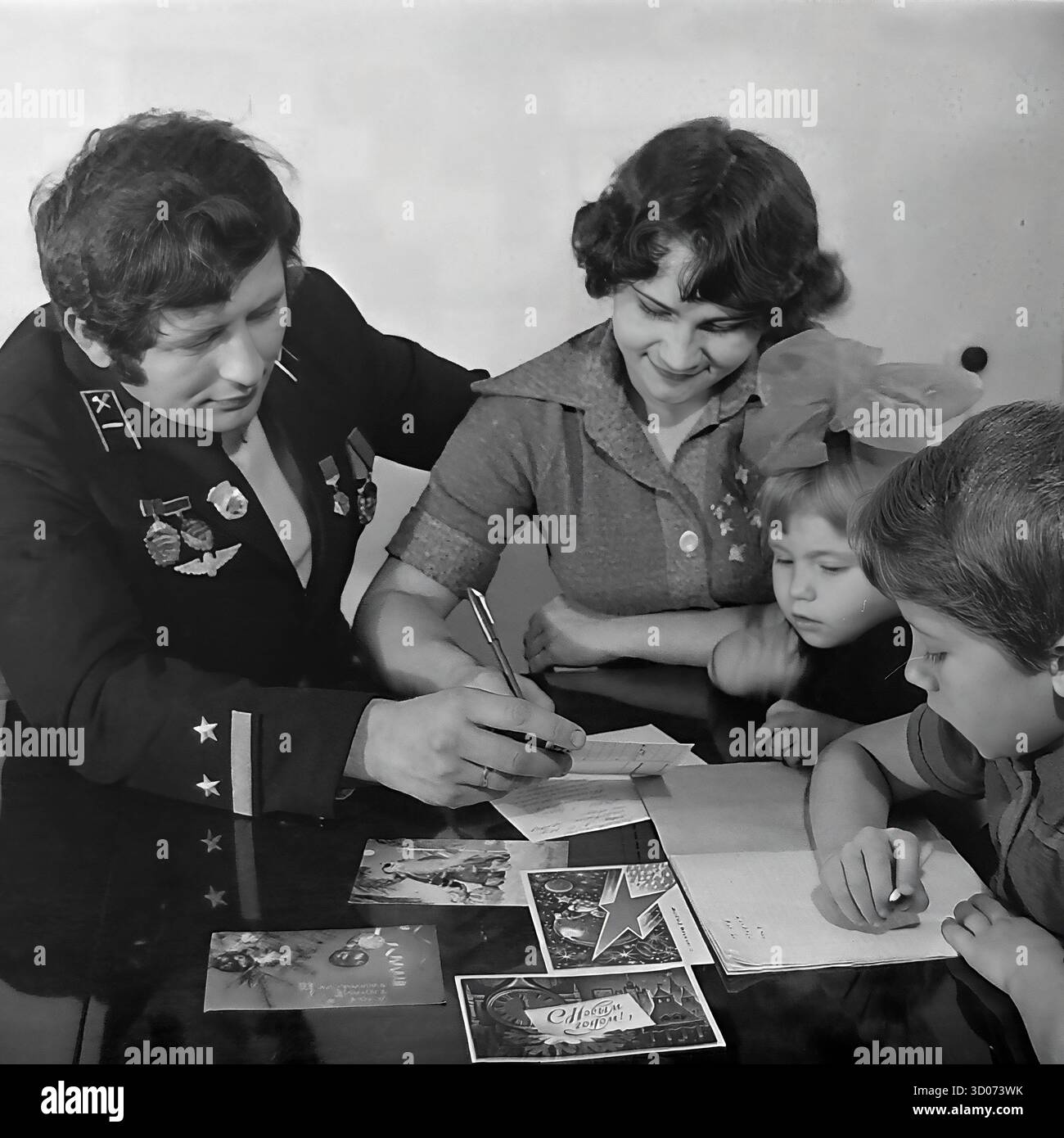 Une heureuse famille soviétique de quatre (père, mère, fils et fille) écrit des cartes de vœux de vacances à la maison à Sloviansk, années 1970-1980 Archive photo en noir et blanc, URSS, RSS d'Ukraine. Le père, machiniste et vétéran, porte son uniforme de chemin de fer officiel avec des médailles. Toute la famille est assise ensemble à la table. Les enfants écrivent aussi. Cette image réconfortante capture une scène de la vie soviétique quotidienne, des traditions familiales et de la parentalité. Un document nostalgique d'une famille heureuse et d'une vie paisible dans le Donbass avant la guerre. Banque D'Images Une heureuse famille soviétique de quatre (père, mère, fils et fille) écrit des cartes de vœux de vacances à la maison à Sloviansk, années 1970-1980 Archive photo en noir et blanc, URSS, RSS d'Ukraine. Le père, machiniste et vétéran, porte son uniforme de chemin de fer officiel avec des médailles. Toute la famille est assise ensemble à la table. Les enfants écrivent aussi. Cette image réconfortante capture une scène de la vie soviétique quotidienne, des traditions familiales et de la parentalité. Un document nostalgique d'une famille heureuse et d'une vie paisible dans le Donbass avant la guerre. Banque D'Images
